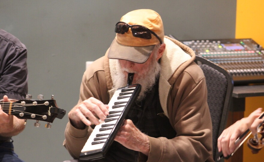 A man in a hat plays the melodica.