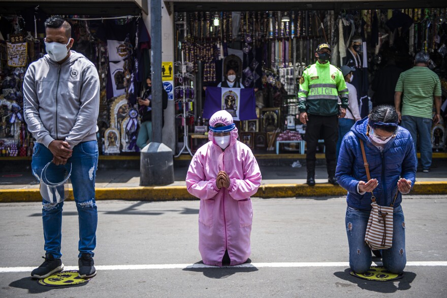 TOPSHOT - Believers remain in the street in front of Las Nazarenas church, praying to the Lord of the Miracles, in Lima on October 08, 2020. - The procession of the Lord of Miracles, which for more than three centuries has been going through Lima streets with thousands of faithful, will be held virtually due to the Covid-19 coronavirus pandemic. (Photo by ERNESTO BENAVIDES / AFP) (Photo by ERNESTO BENAVIDES/AFP via Getty Images)