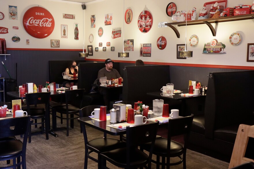 Two patrons at a booth in Little Dipper Diner. Several empty tables and booths surround the patrons