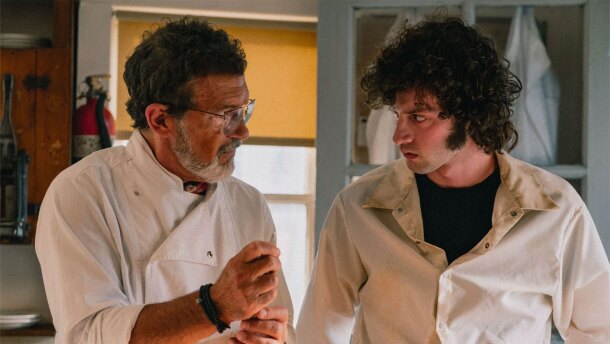 Antonio Banderas as Chef, and Dominic Sessa as a young Anthony Bourdain. Both are wearing white chef smocks