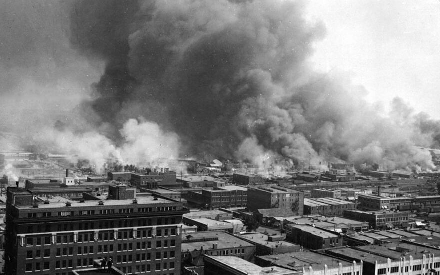 A black and white picture of smoke rising from buildings.