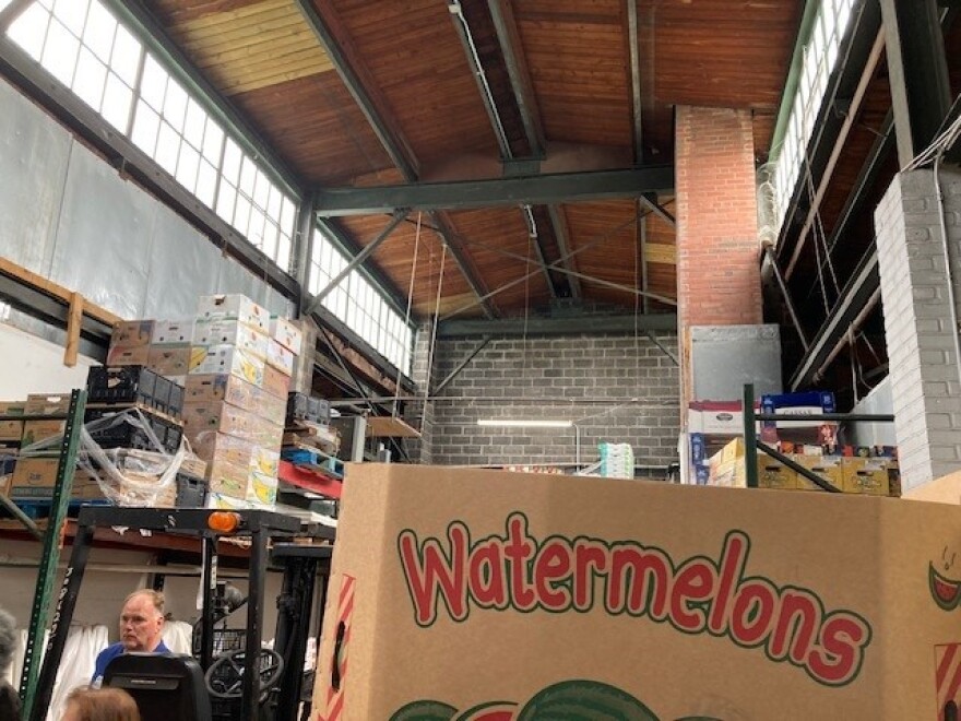 Steel beams support the wooden roof of an old building filled with produce.