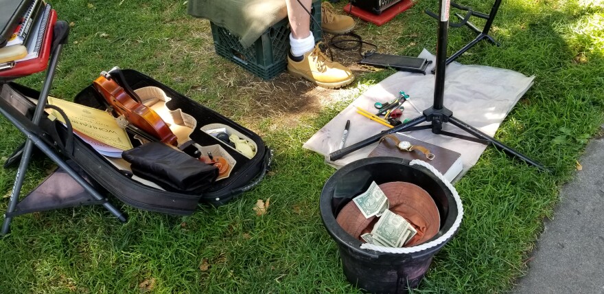 An upside down cap with money in it on the ground.