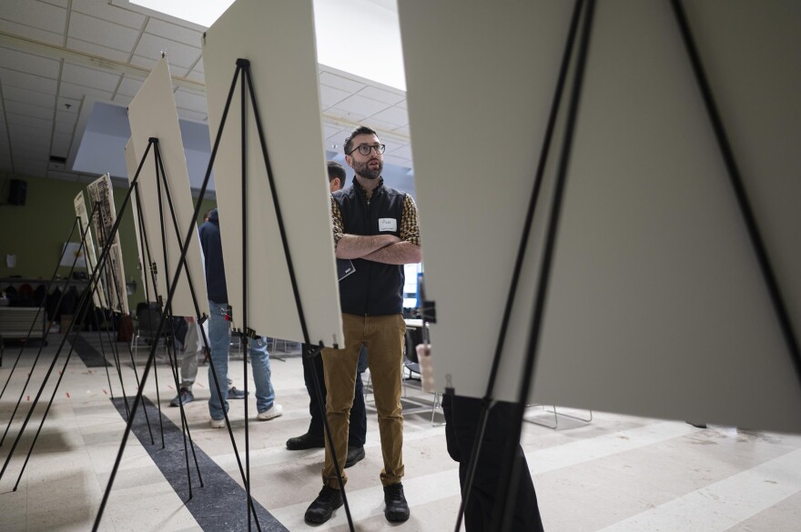 A man stands near a row of posterboards on easels