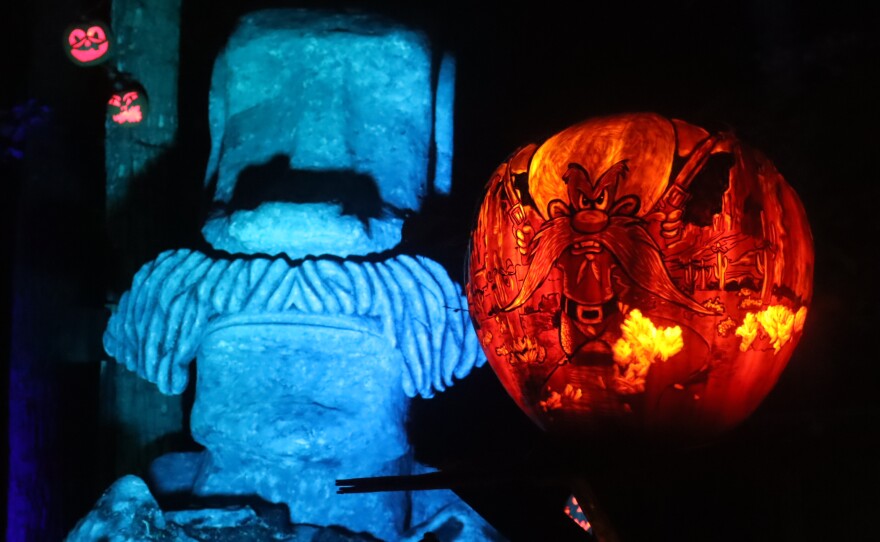 A jack-o-lantern of Yosemite Sam (right) next to an Easter Island statue (left)