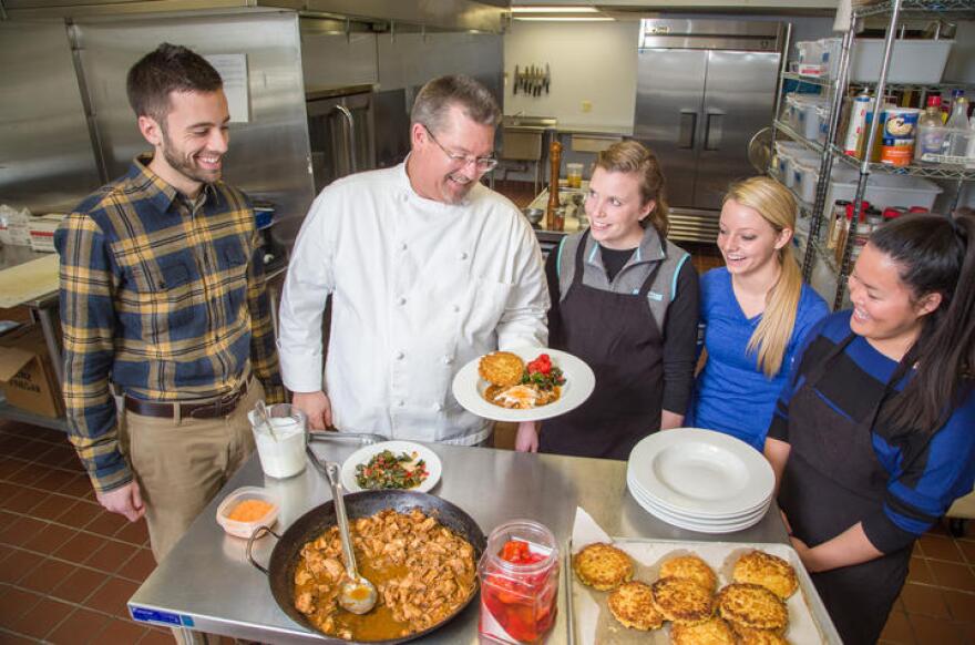 Chef Bob Perry plates up a dish of Ubatuba Paprika Chicken topped with Buttermilk Crème Fresh along with Seared Kale Agrodolce and Cornbread/Rice Cake in the Food Lab, part of the Department of Dietetics and Human Nutrition in the College of Agriculture, Food and Environment at the University of Kentucky. (L to R): Aaron Schwartz, Diatetic Internship Director; Bob Perry, Chef and Food Lab Coordinator; Rachel Thomas, Jordan Brown and Emma Simpson.