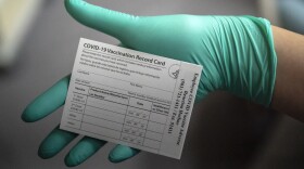 A healthcare worker displays a COVID-19 vaccine record card at the Portland Veterans Affairs Medical Center in December.