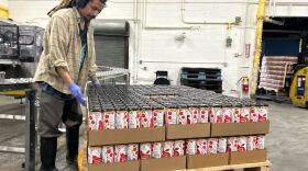 A Nine Pins Ciderworks employee with cases of the company's product. For its cans, the North Albany business needs aluminum sheets imported from Canada. That aluminum is now subject to steep tariffs, raising the company's canning costs.