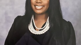 Ja'Maya Clark  wearing graduation robe holding a mortar board hat