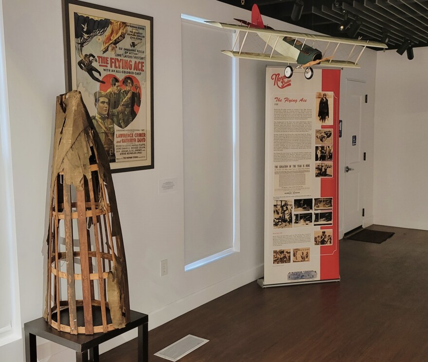 Part of the tail of the full-size airplane prop used in the Norman Studios' 1926 Black film, "The Flying Ace," on display next to a film poster and a model of the biplane at the Norman Studios complex in Arlington.