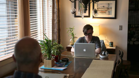 A teenager at a table with a laptop.