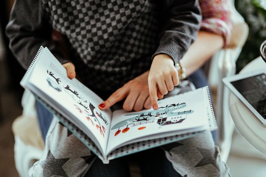 Child reading a book and pointing at page