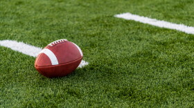 A brown leather american football on a green playing field
