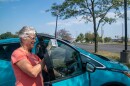 Volunteer Camille Garrison installs the temperature sensor on Betsy Kachmar's car window. The sensor slides over the window and then sits firmly once it's been rolled up.