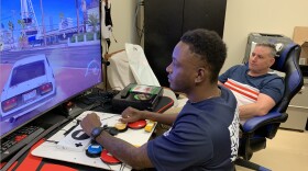 Army veteran Mike Monthervil (left) uses an adaptive controller to play video games as his VA recreational therapist Jamie Kaplan watches.