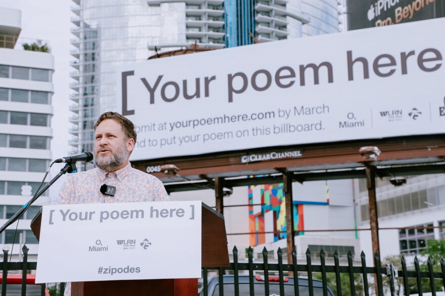 P. Scott Cunningham, founder and executive director of O, Miami, stands in front of a billboard on Biscayne Boulevard that will display a winning Miamian's poem for all of April.