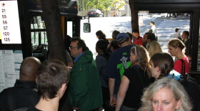 A crowd of passengers makes their way on to a bus.