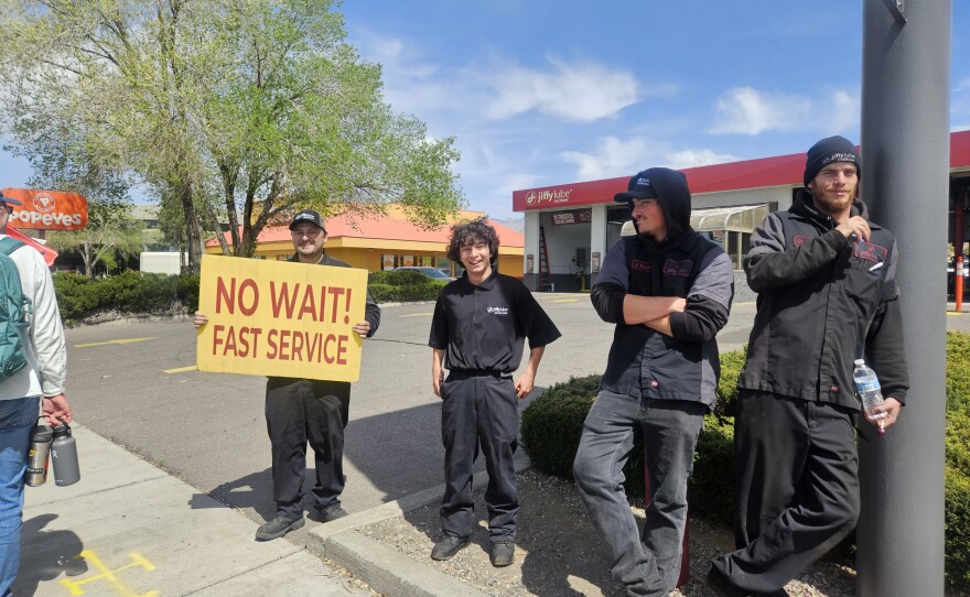 Jiffy Lube workers look to snag some business as marchers stream by during the No Kings protest.