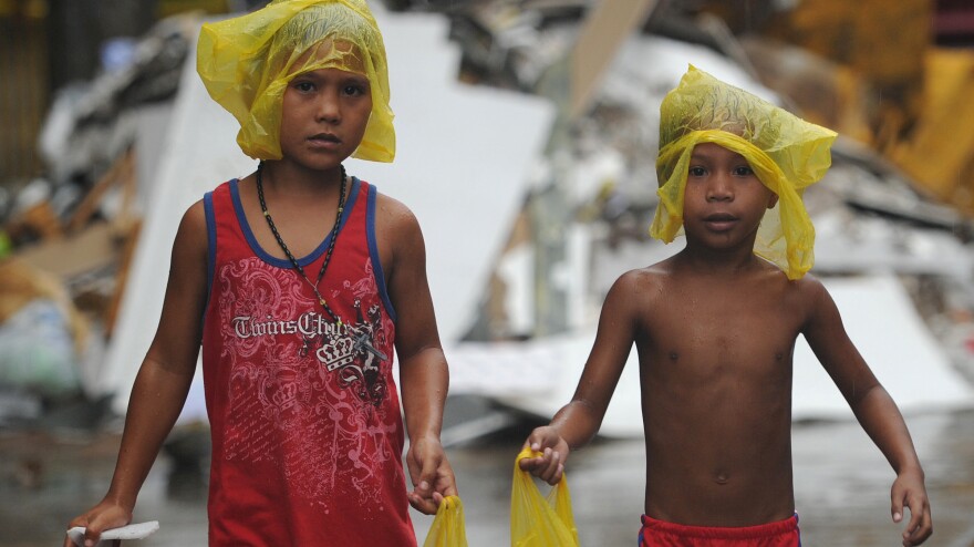 Young survivors of Typhoon Haiyan brave December rain as they ask for gifts from residents in the streets of Tacloban, the Philippines. Months after the storm, cleanup is still ongoing and many of the more than 6,000 dead have yet to be identified.