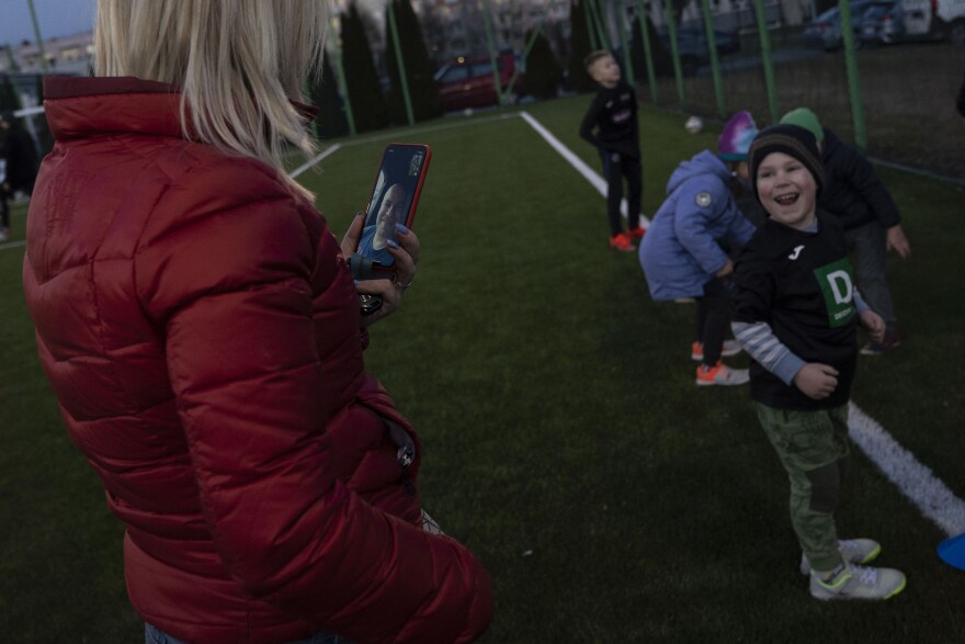 Matvii, 4, smiles as his mother FaceTimes his father, currently serving in the Ukrainian military, during a soccer game for kids at the soccer academy Akademia Pilkarska Rzeszow in Rzeszów, Poland, on March 14.