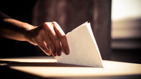 Conceptual image of a person voting, casting a ballot at a polling station, during elections.