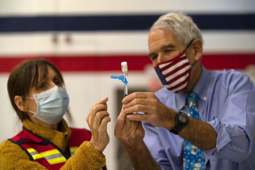 Dr. Sydney Sewall, right, instructs a volunteer while filling a syringe with the COVID-19 vaccine at the Augusta Armory, in this Tuesday, Dec. 21, 2021, file photo, in Augusta, Maine.