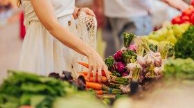 Female hands puts fruits and vegetables in cotton produce bag at food market. Reusable eco bag for shopping. Zero waste concept.