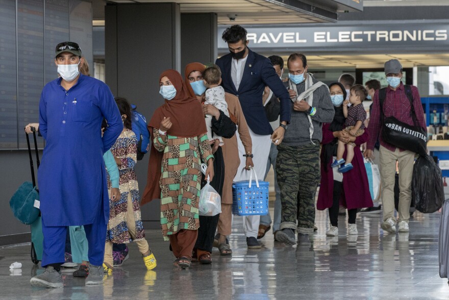 In this Tuesday, Aug. 31, 2021, file photo, families evacuated from Kabul, Afghanistan, walk through the terminal to board a bus after they arrived at Washington Dulles International Airport, in Chantilly, Va. U.S. religious groups of many faiths are gearing up to assist the thousands of incoming refugees.