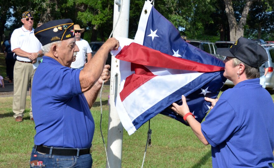 Post 483 EJ Cates and Diane Bosscher raise the flag over Oaklawn Cemetery.