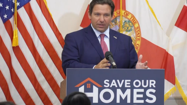 Man speaking at podium in front of an American flag