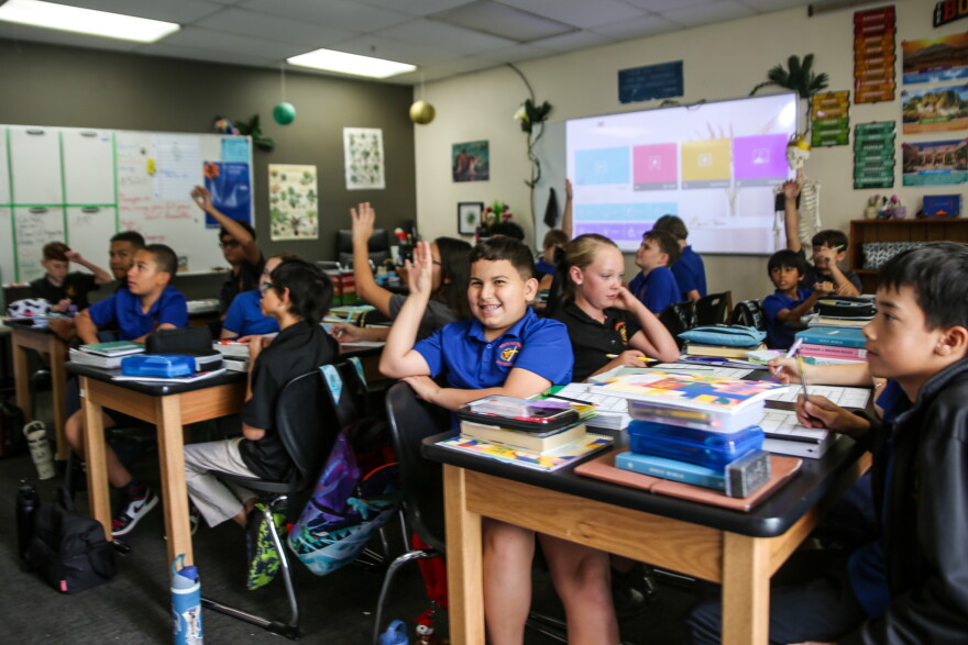 A Southwestern Christian student raising their hand can't resist looking up and smiling at the camera.