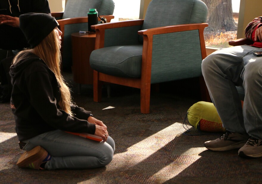 Dr. Mo with Midwest Street Medicine kneels to talk with a man in the Siouxland Downtown Library in Sioux Falls, S.D., on Nov. 17, 2025.