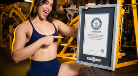 Lilian Zamora Alonso posing with the Guiness World Record certificate for heaviest weighted hip thrust by a woman.