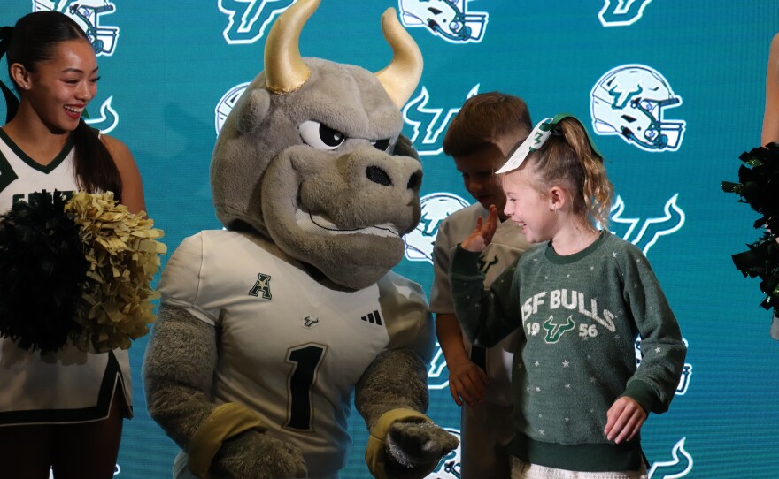 A little girl high-fives USF mascot Rocky