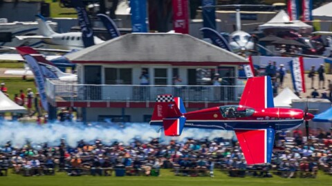 Red airplane flies over crowd 