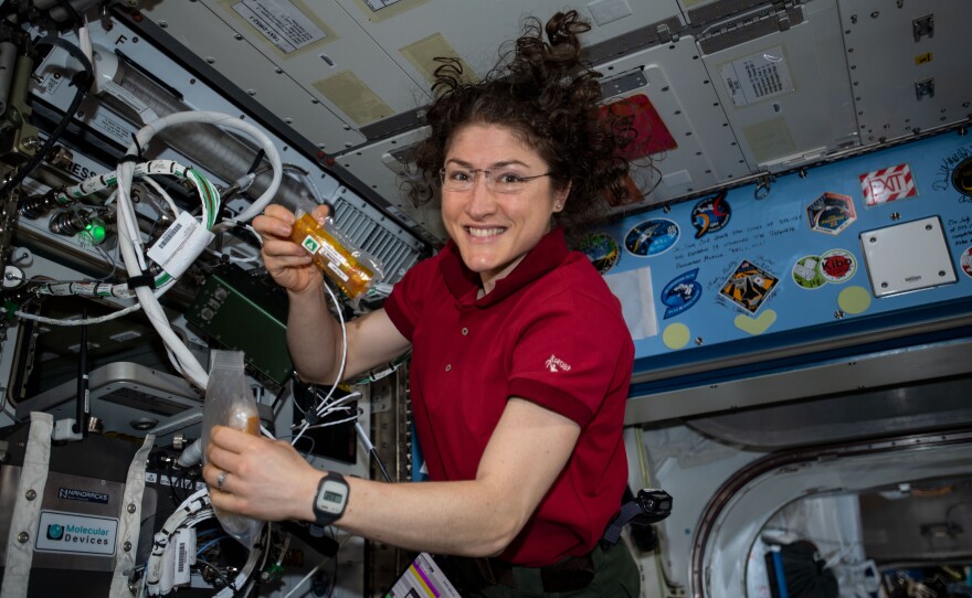 Astronaut Christina Koch holds up a tube on the International Space Station.