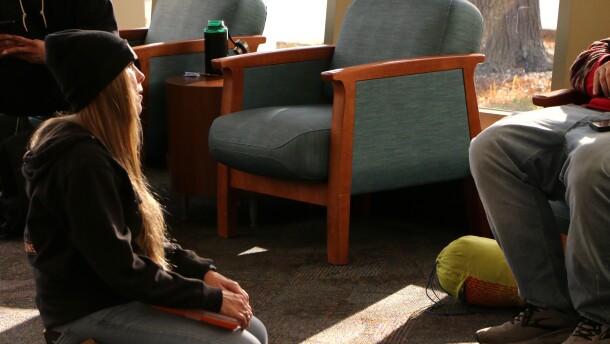 Dr. Mo with Midwest Street Medicine kneels to talk with a man in the Siouxland Downtown Library in Sioux Falls, S.D., on Nov. 17, 2025.