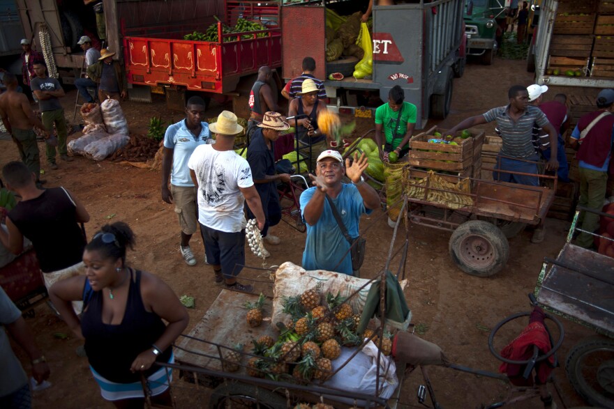 A vendor reaches out to catch a pineapple at a food market in the outskirts of Havana.