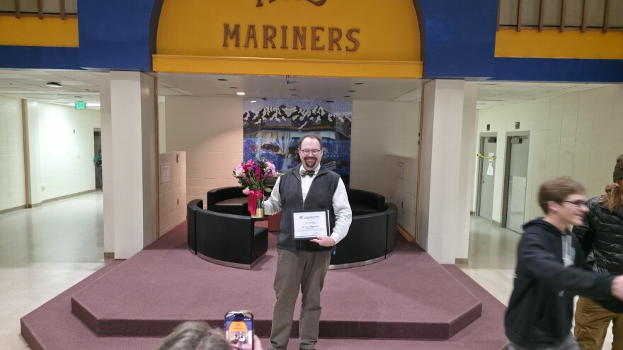 Homer High School choir teacher Kyle Schneider holds the NFHS Outstanding Music Educator Award in the school’s commons on Monday, Jan. 19, 2026.