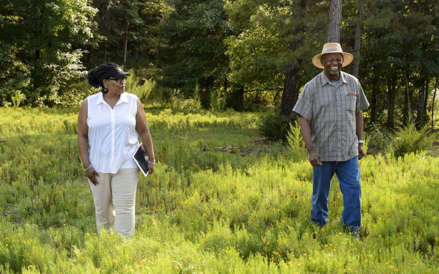 Monica White walks in a field with a farmer.