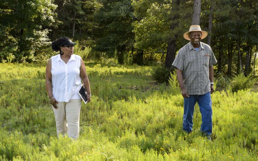 Monica White walks in a field with a farmer.