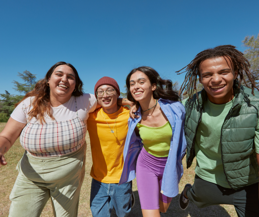 four teenagers walking and smiling towards the camera