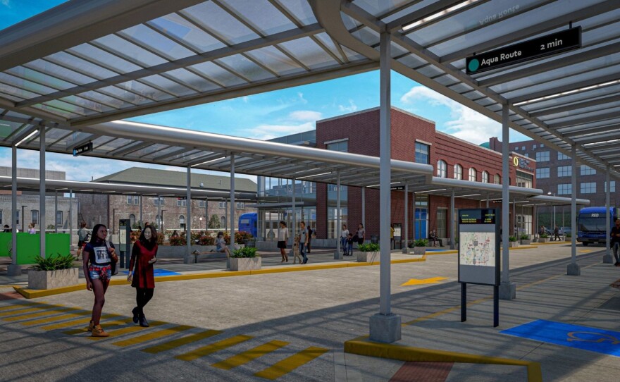 A computer design of the boarding area of the new facility. From the inside, several people are walking around the drive-up area for buses.