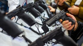We see hands holding guns that are on display in a store