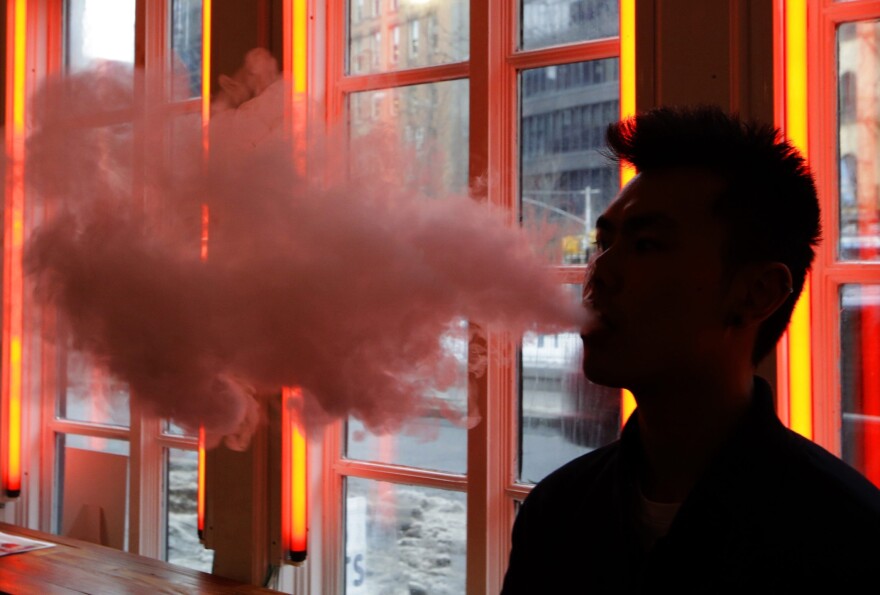 FILE - In this Feb. 20, 2014, File photo, a patron exhales vapor from an e-cigarette at the Henley Vaporium in New York. New York has added electronic cigarettes to its indoor smoking ban, making it illegal to use the devices in bars, restaurants and most workplaces. Democratic Gov. Andrew Cuomo, who signed the bill into law Monday, Oct. 23, 2017. (AP Photo/Frank Franklin II, File)