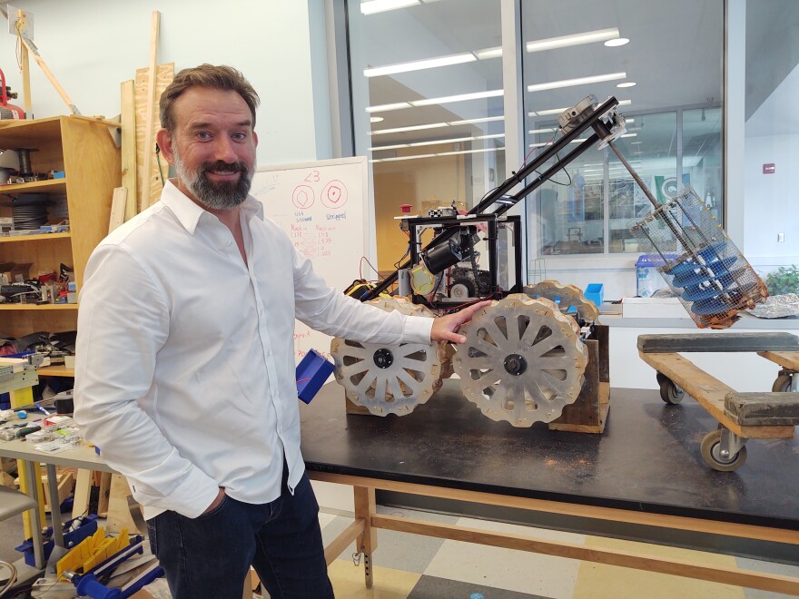 Dr. Jaromy Kuhl, dean of the UWF College of Science and Engineering, shows off a rover developed by students in one of their robotics labs.