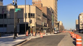 Orange construction barrels block the left-hand lane of Adams Street near the intersection with Fulton Street in downtown Peoria. 