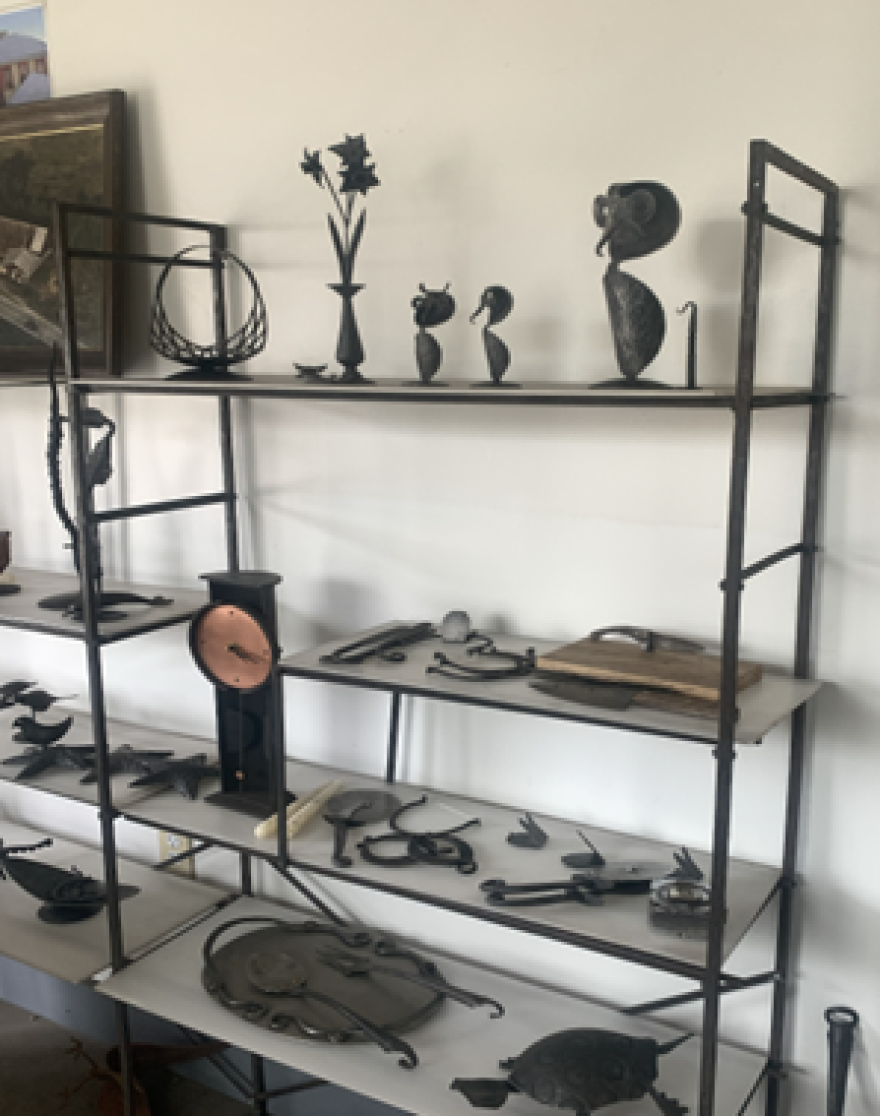 A black shelf against a white wall with metal sculptures on it.