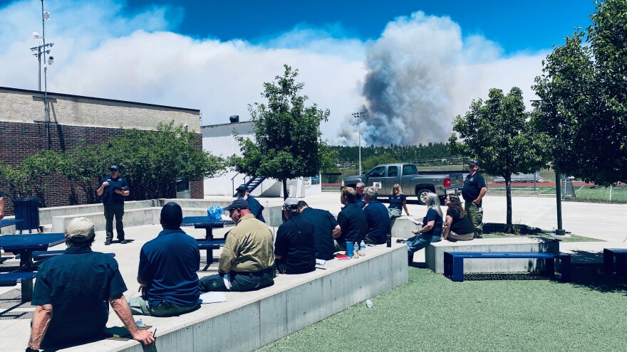 Members of the Alaska Complex Incident Command Team meet outside the incident command post in Rye, Colorado as smoke rises from the nearby Aspen Acres Fire on July 1, 2026.