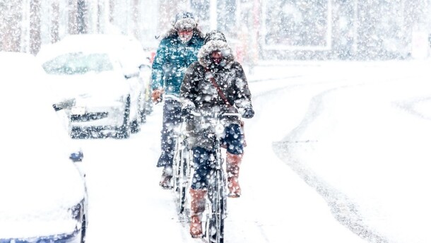 Two people biking on a snowy city street